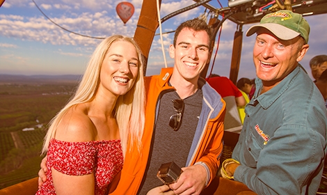 Hot Air Balloon pilot with happy passengers in basket smiling to camera